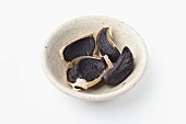 Cloves of black garlic in small dish