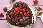 Schokoladenkuchen mit Schlagsahne und Erdbeeren in Herzform