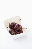 Several cherries in a paper dish