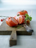 Whole and halved beefsteak tomato on a chopping board