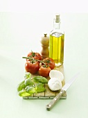 Olive oil, tomatoes, basil & mozzarella on chopping board