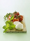 Tomatoes, basil and mozzarella on chopping board