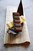Schokoladenstücke von weisser und dunkler Schokolade auf Kakaofruchtschale