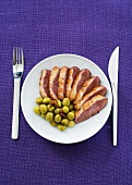 Sliced duck breast with olives