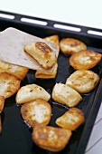 Roast potatoes on baking tray with spatula