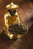 Gilded statuette with bowl of black peppercorns
