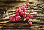 Pink pepper on wooden background