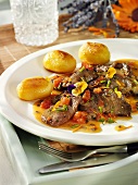 Slices of lamb with edible flowers and roast potatoes