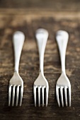 Three silver forks on wooden background