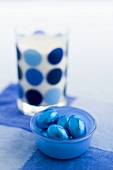 Chocolate eggs in blue foil and glass of milk