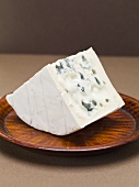Piece of blue cheese on wooden plate