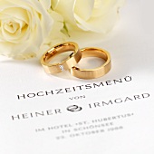 Wedding menu, wedding rings and white roses