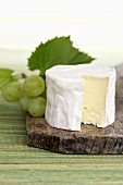 Soft cheese and green grapes on chopping board