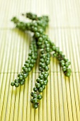 Clusters of green peppercorns on bamboo mat