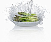 Pouring water onto green asparagus