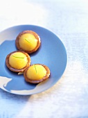 Three lemon tartlets on blue plate