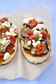 Two pita bread pizzas with aubergines, cherry tomatoes, feta