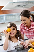Mutter und Tochter beim Orangen auspressen in der Küche