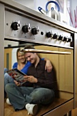 Seated couple reflected in oven door