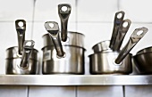 Pans of various sizes on a kitchen shelf