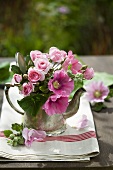 Hollyhocks and roses (Evelyn) in pewter teapot out of doors