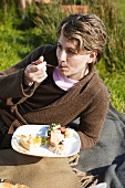 Frau liegt auf einer Picknickdecke und isst