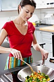 Woman frying vegetables in wok frying pan
