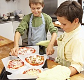 Two boys making pizzas