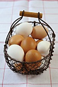 White and brown eggs in a wire basket