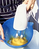 Mixing egg yolk and sugar with an electric hand mixer