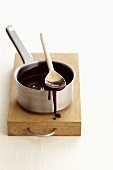 Chocolate sauce running down side of pan & on wooden spoon