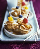 Crepes on cocktail sticks with fruit and syrup