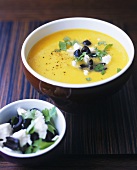 Yellow pepper cream soup with feta, olives and parsley