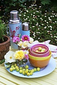 Flowers, bowls and Thermos flasks on table out of doors