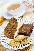 Plate of cakes & biscuits in front of cup of tea with milk