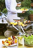 Grillszene im Garten, Frau mit Grillteller im Hintergrund