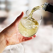 Weißwein in ein Glas gießen