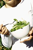Young woman eating mixed green vegetable salad