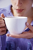 Young woman blowing on a cup of hot tea