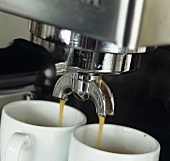 Espresso läuft in zwei Tassen