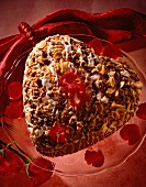 A heart-shaped almond cake decorated with rose petals