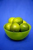Limes in a bowl against a blue background