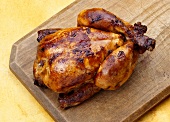 A whole grilled chicken on a wooden board