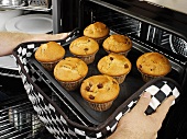 Man taking muffins out of the oven