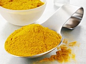 Ground turmeric on a spoon and in a glass bowl
