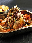 Stuffed lamb shank with vegetables & rosemary in roasting dish