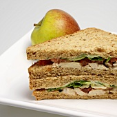 Hähnchen-Sandwich mit mit Salat, Tomaten und einem Apfel