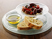 Olives in oil in a small glass dish with white bread
