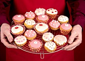 Man holding cupcakes on cake rack