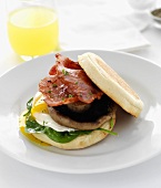 Bacon, mushroom, fried egg and spinach on English muffin